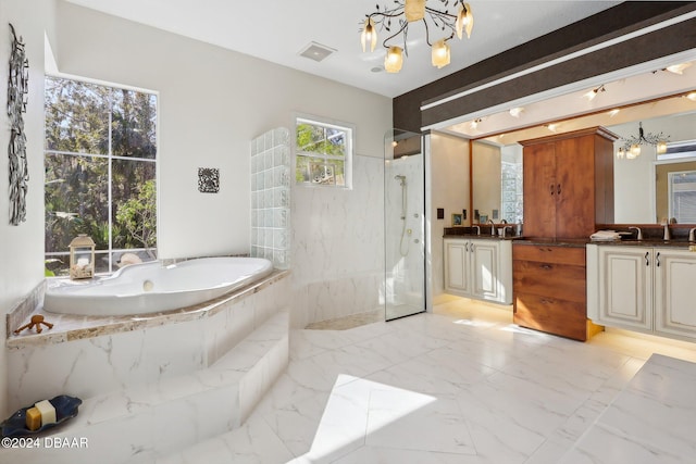 bathroom with a notable chandelier, vanity, and independent shower and bath