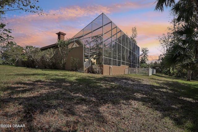 exterior space featuring a yard and glass enclosure