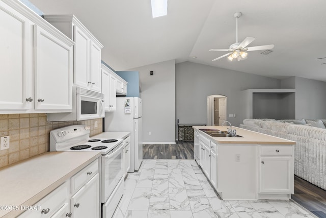 kitchen featuring white appliances, open floor plan, a kitchen island with sink, vaulted ceiling, and a sink