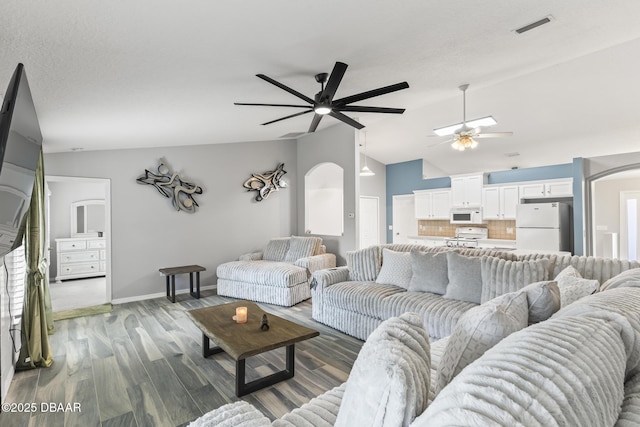 living room featuring arched walkways, ceiling fan, lofted ceiling, wood finished floors, and visible vents