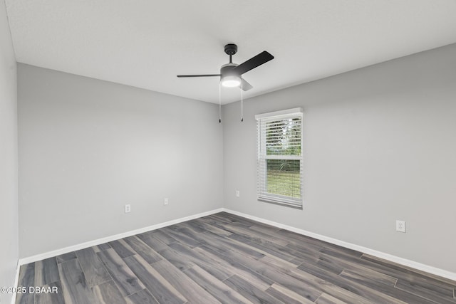 spare room with ceiling fan, dark wood-type flooring, and baseboards