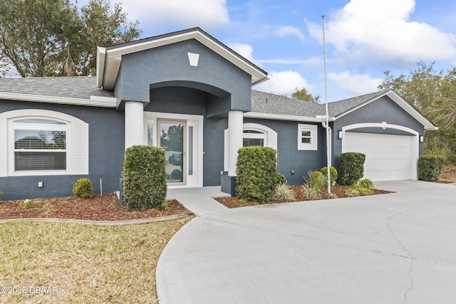 ranch-style house featuring a garage, driveway, a shingled roof, and stucco siding