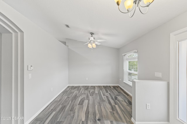 spare room featuring ceiling fan with notable chandelier, visible vents, baseboards, and wood finished floors