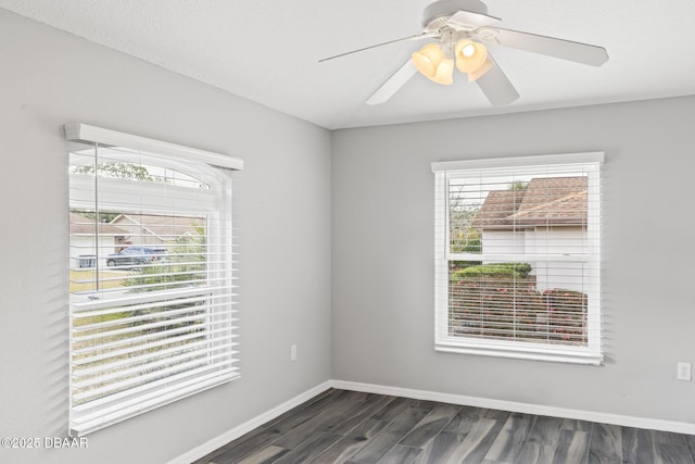 unfurnished room featuring baseboards, dark wood finished floors, and a healthy amount of sunlight