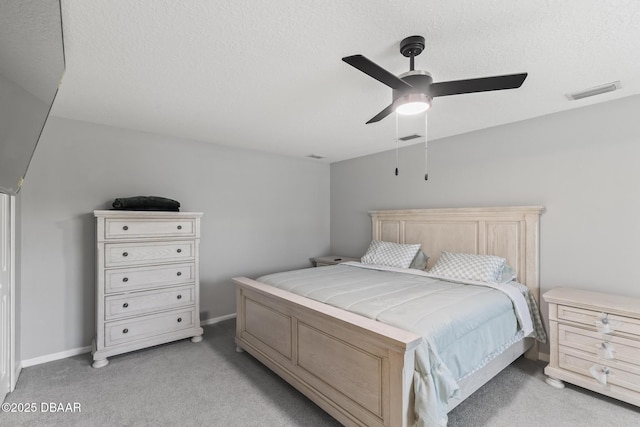 bedroom with baseboards, visible vents, light carpet, and a textured ceiling