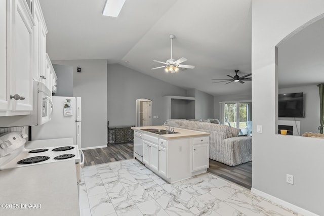 kitchen featuring white appliances, lofted ceiling, open floor plan, white cabinetry, and a sink