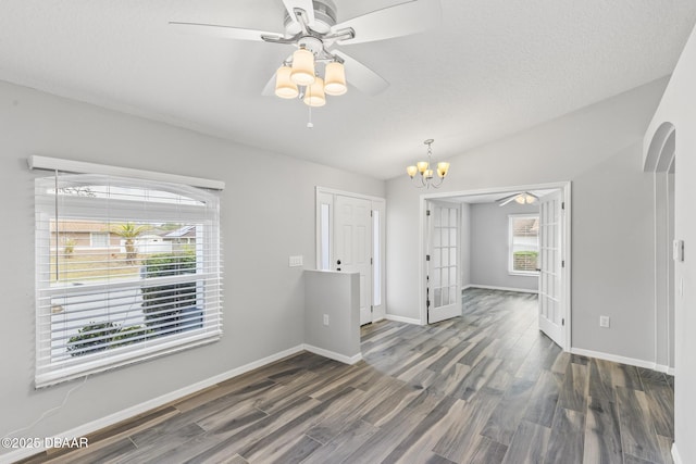 empty room featuring arched walkways, ceiling fan with notable chandelier, wood finished floors, and lofted ceiling