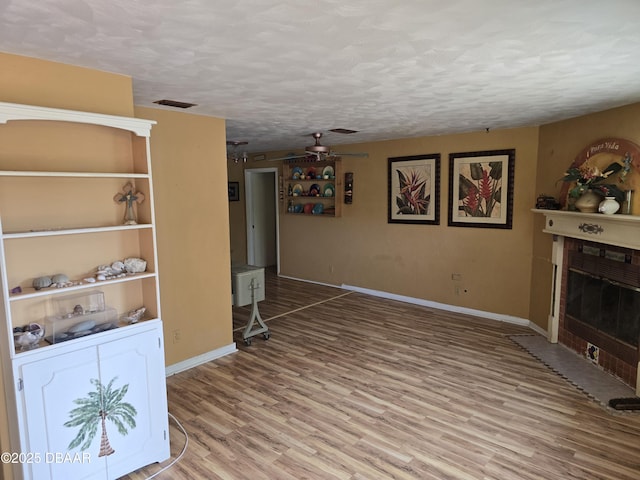 unfurnished living room featuring a textured ceiling, wood finished floors, visible vents, and baseboards