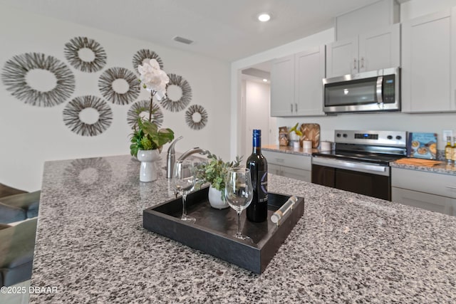 kitchen with light stone countertops, white cabinets, and appliances with stainless steel finishes