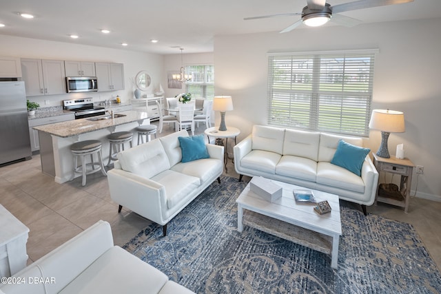 living area with recessed lighting, baseboards, light tile patterned floors, and ceiling fan with notable chandelier