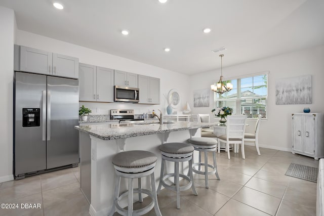 kitchen with light stone counters, visible vents, light tile patterned flooring, stainless steel appliances, and a kitchen bar