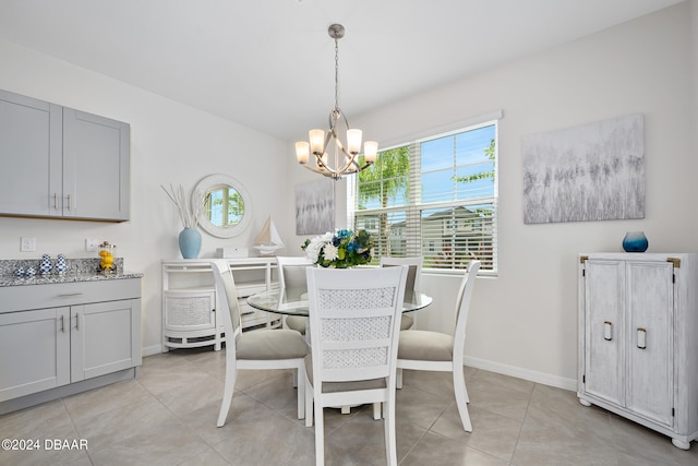 dining area with a notable chandelier, light tile patterned flooring, and baseboards