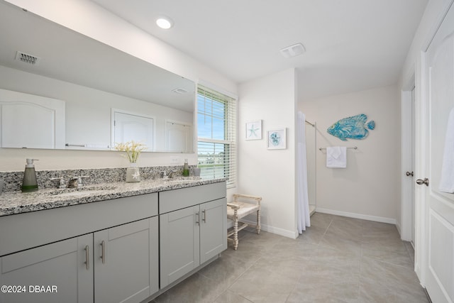 full bath with tile patterned flooring, visible vents, baseboards, double vanity, and a sink