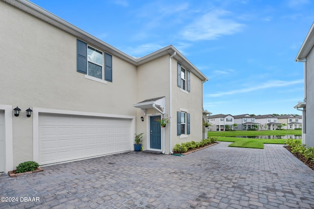 view of front facade featuring a front lawn, a residential view, stucco siding, decorative driveway, and an attached garage