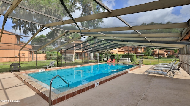 view of pool featuring glass enclosure, a patio area, and a lawn