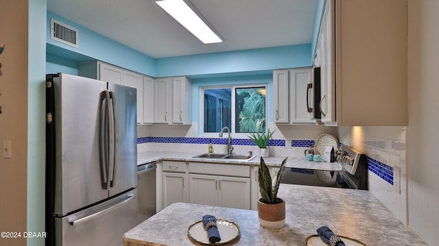 kitchen featuring stainless steel appliances, white cabinetry, tasteful backsplash, and sink