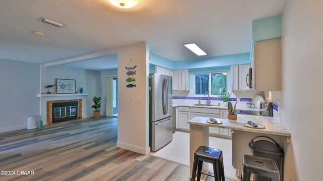 kitchen featuring white cabinetry, sink, stainless steel appliances, hardwood / wood-style floors, and a breakfast bar