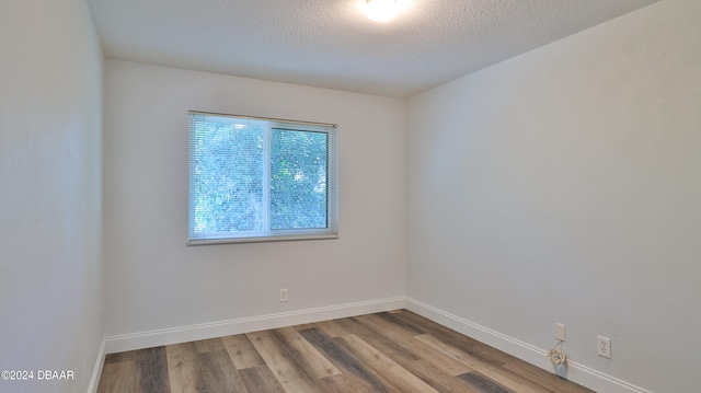 empty room with hardwood / wood-style floors and a textured ceiling