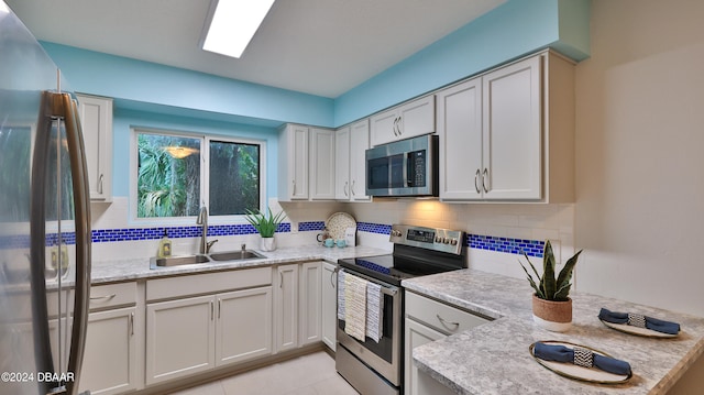 kitchen featuring sink, decorative backsplash, light stone countertops, appliances with stainless steel finishes, and light tile patterned flooring