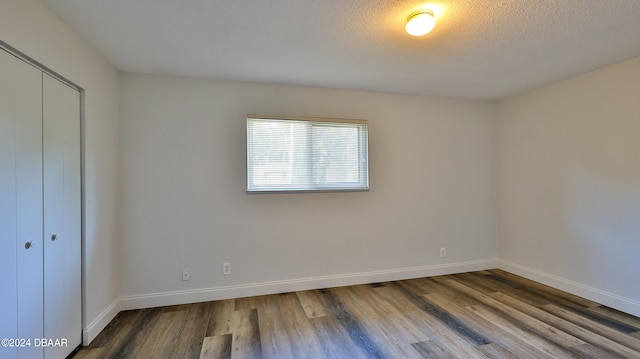 unfurnished bedroom featuring a closet, a textured ceiling, and hardwood / wood-style flooring