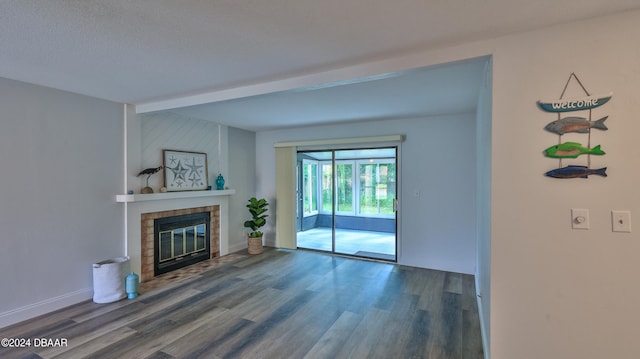 unfurnished living room with a fireplace, beam ceiling, a textured ceiling, and hardwood / wood-style flooring