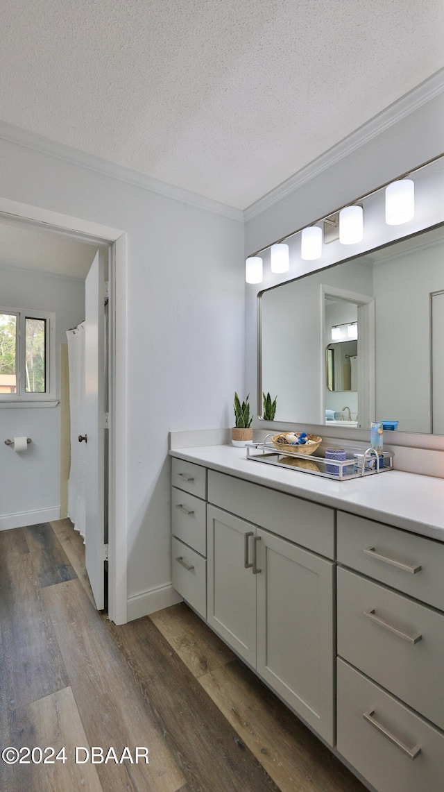 bathroom with hardwood / wood-style floors, vanity, crown molding, a textured ceiling, and curtained shower