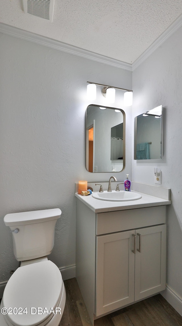 bathroom with vanity, a textured ceiling, crown molding, wood-type flooring, and toilet