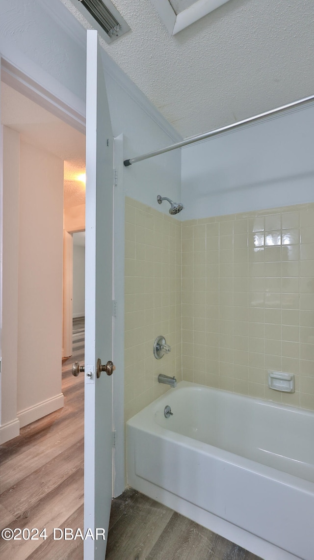 bathroom featuring hardwood / wood-style floors, tiled shower / bath combo, and a textured ceiling