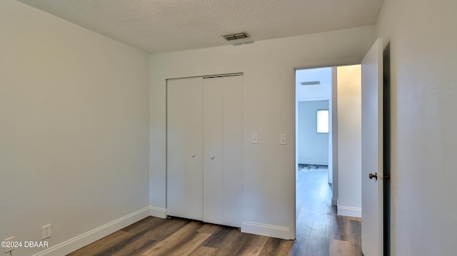 unfurnished bedroom with dark hardwood / wood-style floors, a textured ceiling, and a closet