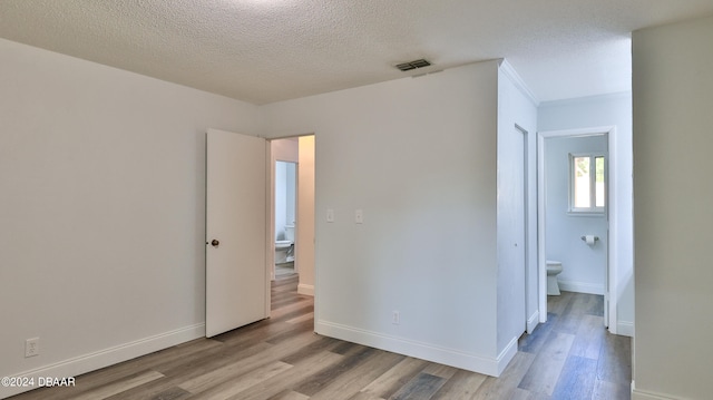 spare room featuring a textured ceiling and light hardwood / wood-style flooring