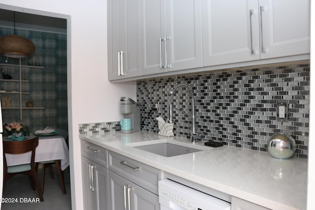 kitchen featuring light stone countertops, sink, white cabinetry, backsplash, and dishwashing machine