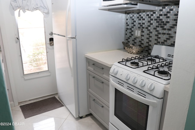 kitchen featuring backsplash, white gas range, gray cabinetry, and light tile patterned floors