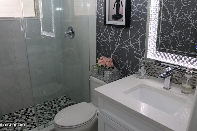 bathroom with vanity, toilet, an enclosed shower, and backsplash