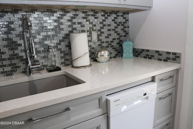 kitchen with dishwasher, sink, decorative backsplash, light stone countertops, and white cabinetry