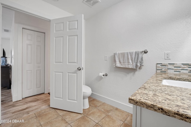 bathroom featuring tasteful backsplash, vanity, tile patterned floors, and toilet