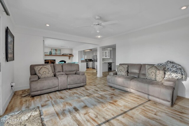 living room featuring ceiling fan, light wood-type flooring, and ornamental molding