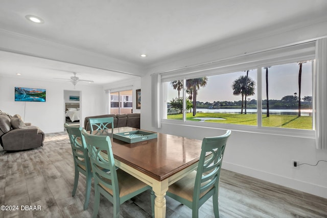 dining area featuring ornamental molding, hardwood / wood-style floors, a water view, and ceiling fan