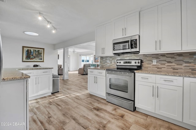 kitchen featuring light wood-type flooring, white cabinetry, light stone counters, and stainless steel appliances