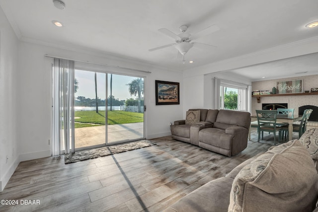 living room featuring ornamental molding, a fireplace, light hardwood / wood-style flooring, and ceiling fan