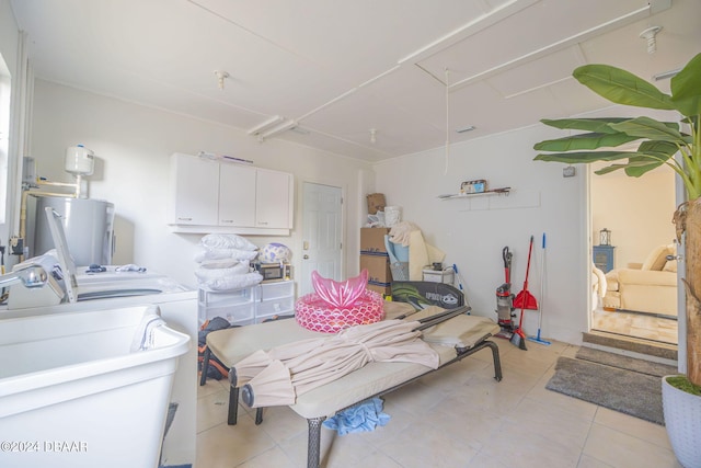 laundry area with electric water heater, washing machine and dryer, cabinets, and light tile patterned floors