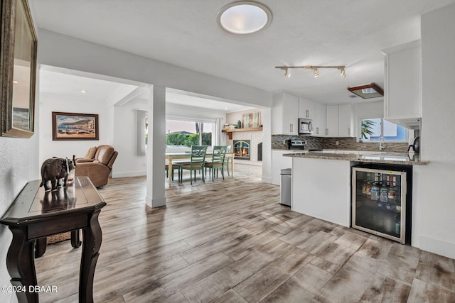 kitchen featuring white cabinets, stainless steel appliances, a healthy amount of sunlight, and beverage cooler