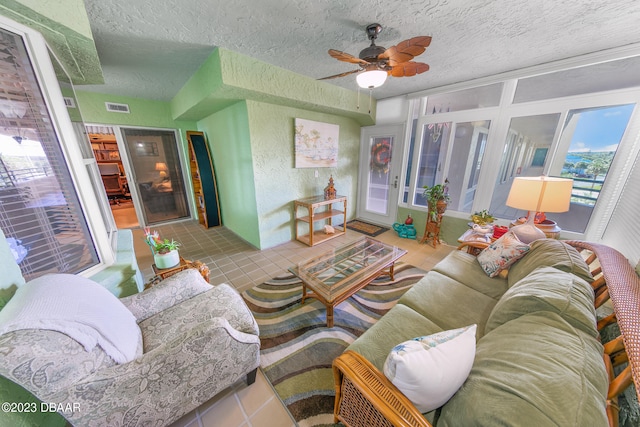 living room with ceiling fan, a textured ceiling, and light tile patterned floors