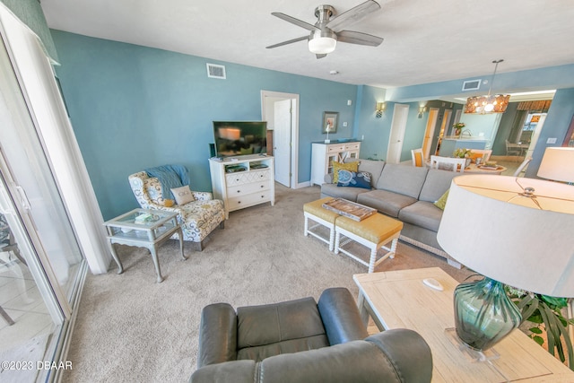 carpeted living room featuring ceiling fan with notable chandelier