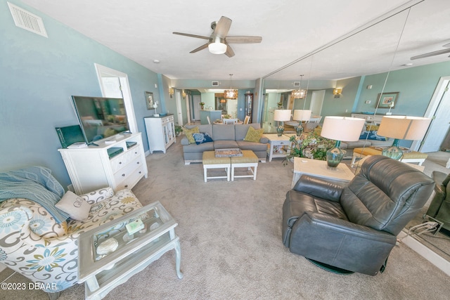 living room with ceiling fan with notable chandelier and light colored carpet