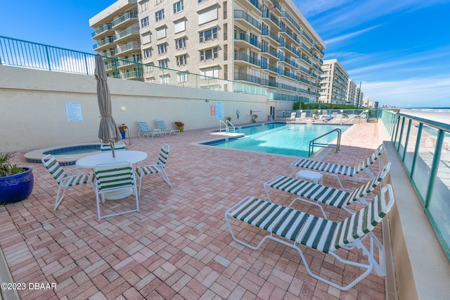 view of swimming pool featuring a patio and a hot tub