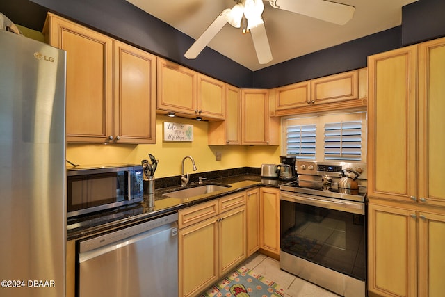 kitchen featuring stainless steel appliances, sink, dark stone counters, ceiling fan, and light tile patterned floors