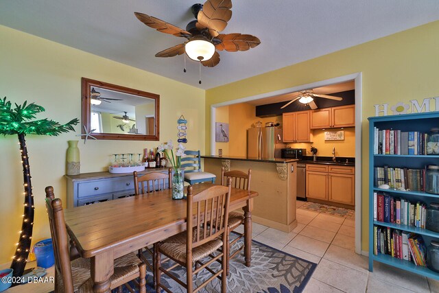 dining space with sink, light tile patterned floors, and ceiling fan