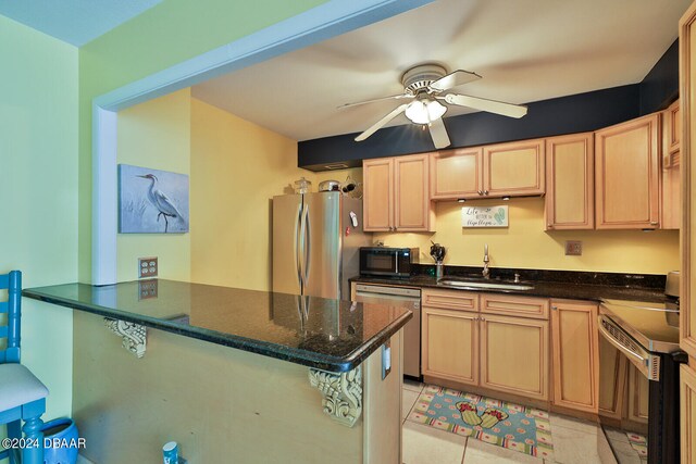 kitchen with dark stone counters, kitchen peninsula, appliances with stainless steel finishes, and sink