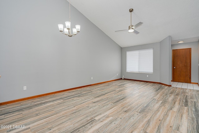 spare room with ceiling fan with notable chandelier, light hardwood / wood-style floors, and lofted ceiling