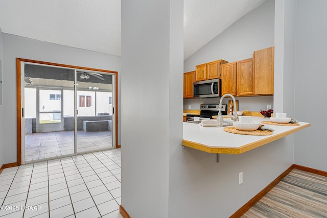 kitchen featuring kitchen peninsula, appliances with stainless steel finishes, a breakfast bar, and lofted ceiling